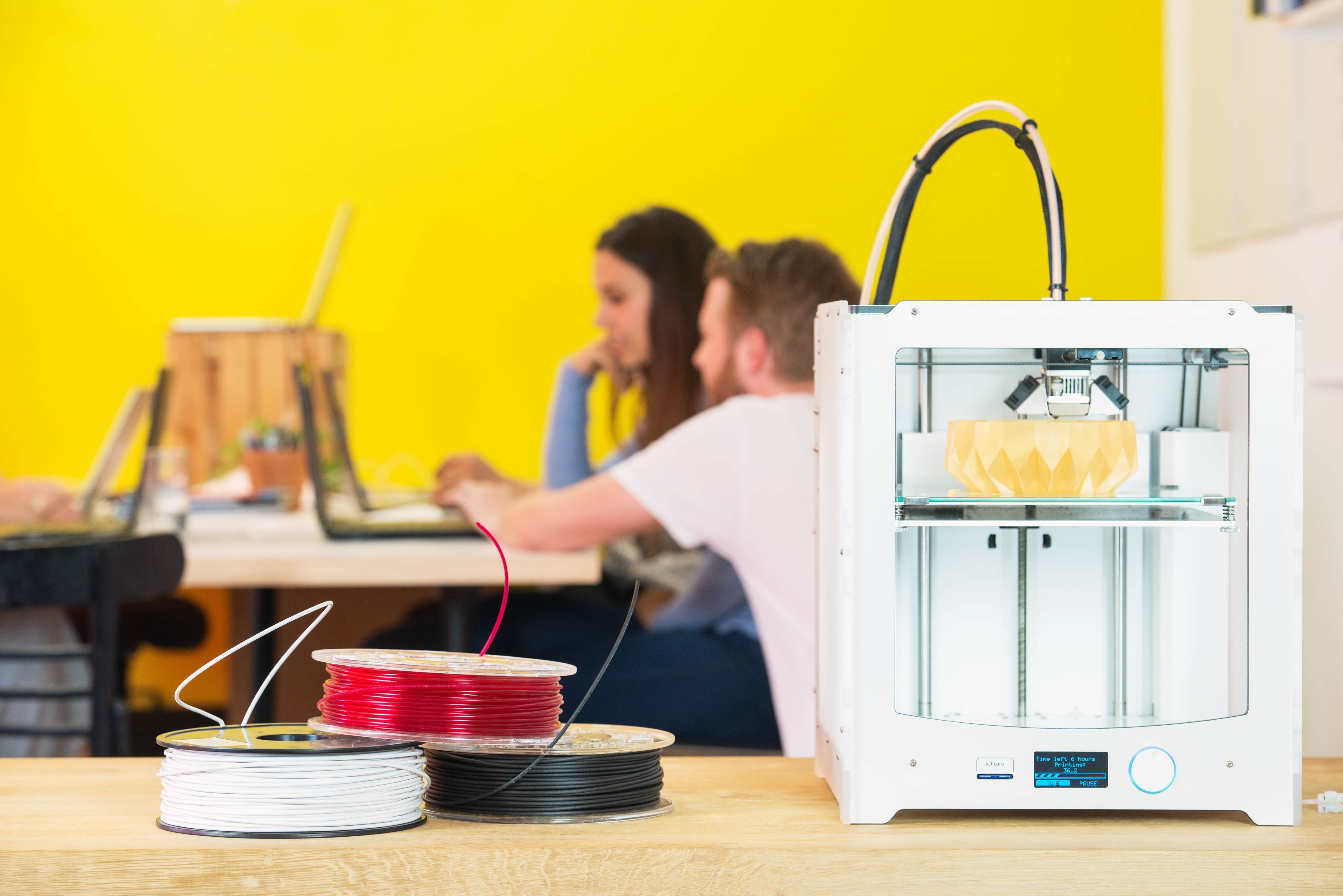 two architects in design agency with close-up of 3d printer