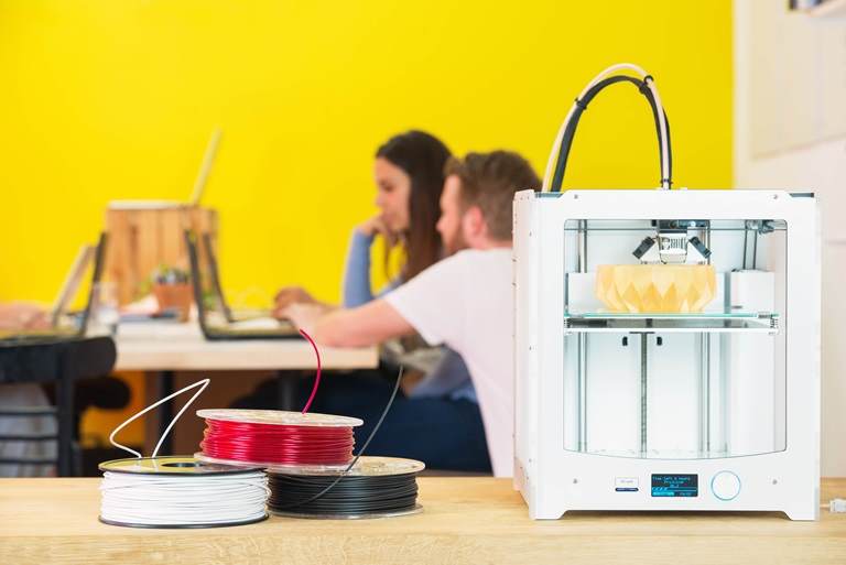 two architects in design agency with close-up of 3d printer